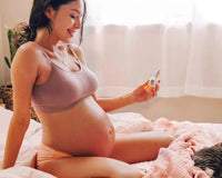 Pregnant woman sitting on a bed using No B.S products