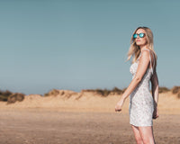 Woman wearing Coral Eyewear sunglasses walking on a beach