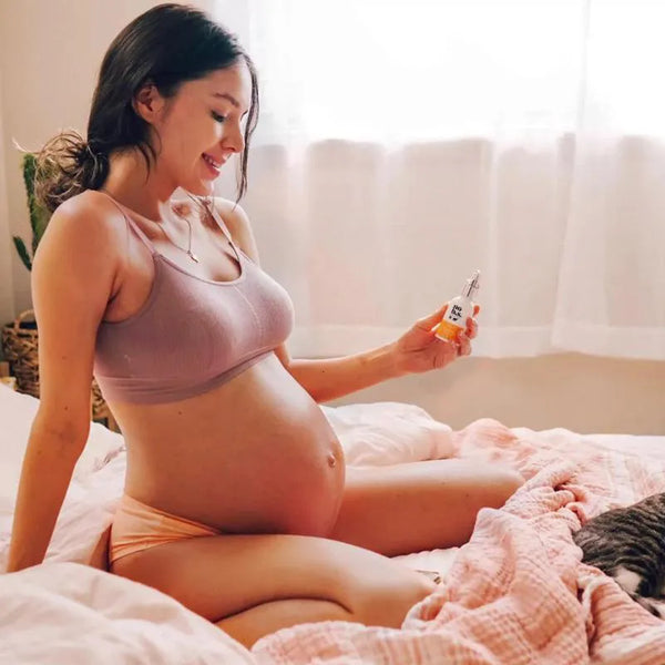 Pregnant woman sitting on a bed using No B.S products