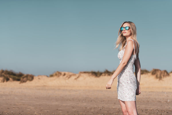 Woman wearing Coral Eyewear sunglasses walking on a beach
