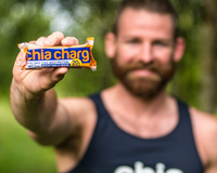 a man in a chia charge black vest holding a chia charge bar