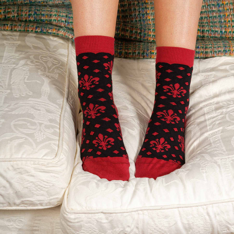 Woman standing on a sofa wearing black Fleur De Lis luxury women's socks from Peper Harow