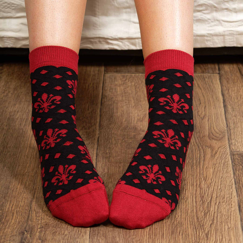 Woman sitting on a sofa wearing black Fleur De Lis luxury women's socks from Peper Harow