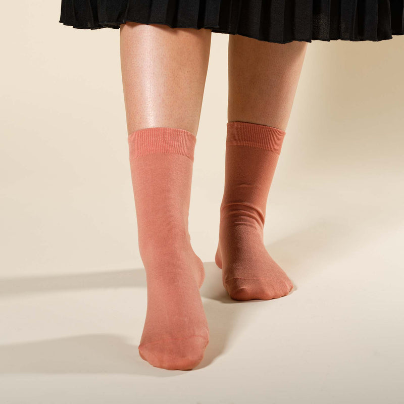 Woman wearing a black skirt and Peper Harow peach Classic women's luxury socks