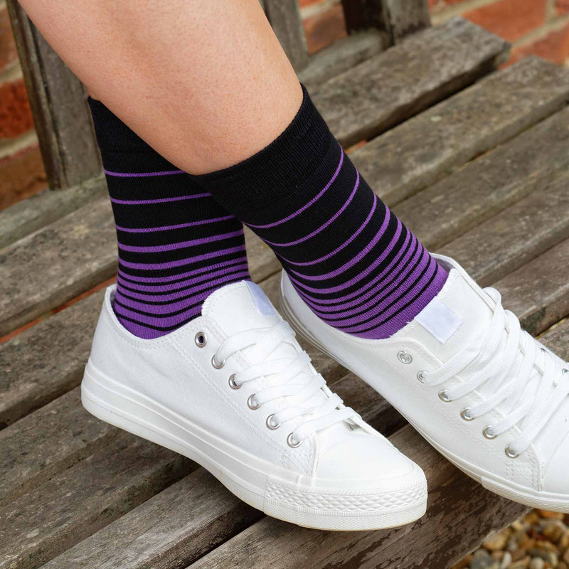 Woman with her feet up on a bench wearing Peper Harow Purple Retro Stripe women's luxury socks